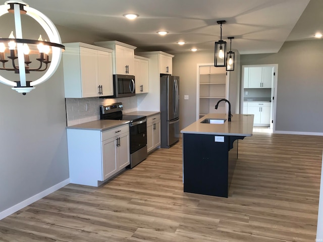 kitchen with baseboards, light wood-style flooring, appliances with stainless steel finishes, and a sink