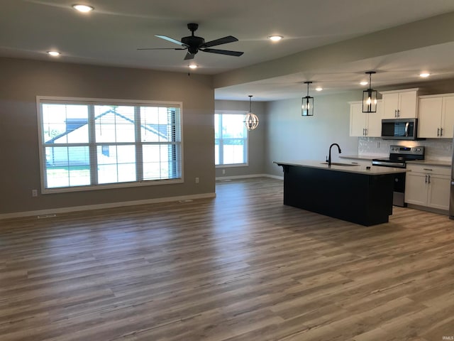 kitchen with dark wood-style floors, open floor plan, a sink, stainless steel appliances, and backsplash