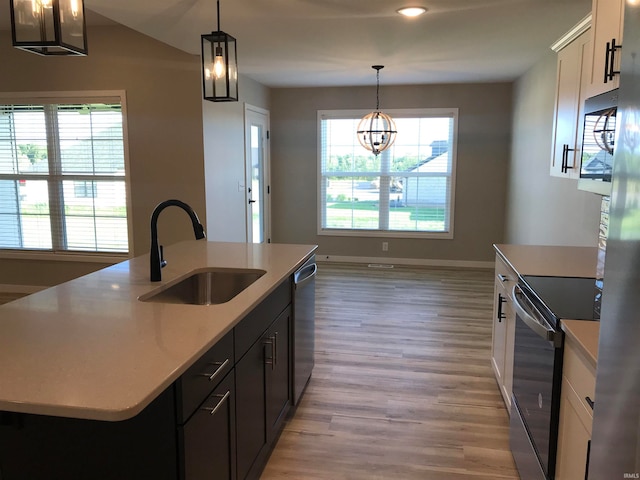 kitchen featuring appliances with stainless steel finishes, light countertops, light wood-style floors, white cabinetry, and a sink