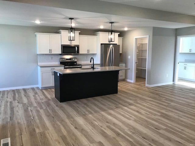 kitchen with stainless steel appliances, visible vents, backsplash, a sink, and light wood-type flooring