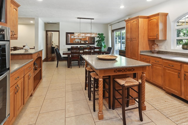 kitchen with decorative light fixtures, a kitchen island, plenty of natural light, and a breakfast bar