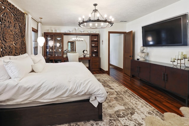 bedroom featuring dark wood-type flooring, an inviting chandelier, and a textured ceiling