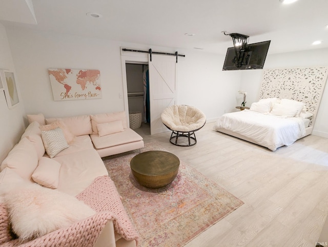 bedroom featuring a barn door and light hardwood / wood-style floors