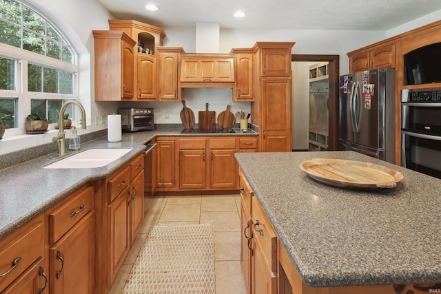 kitchen featuring appliances with stainless steel finishes, light tile patterned floors, a center island, and sink