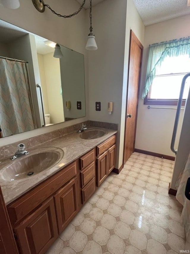 bathroom with toilet, a textured ceiling, and vanity