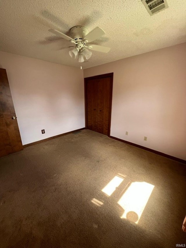 unfurnished bedroom with a textured ceiling, dark carpet, ceiling fan, and a closet