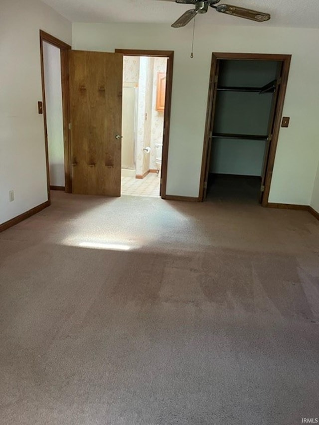 unfurnished bedroom featuring a closet, light colored carpet, ensuite bathroom, and ceiling fan