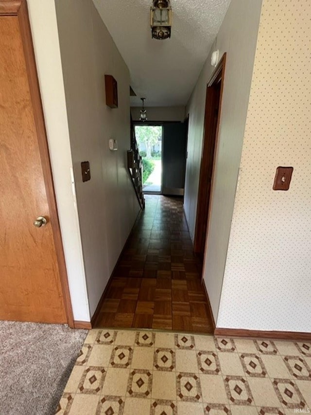 corridor with a textured ceiling, dark parquet flooring, and lofted ceiling