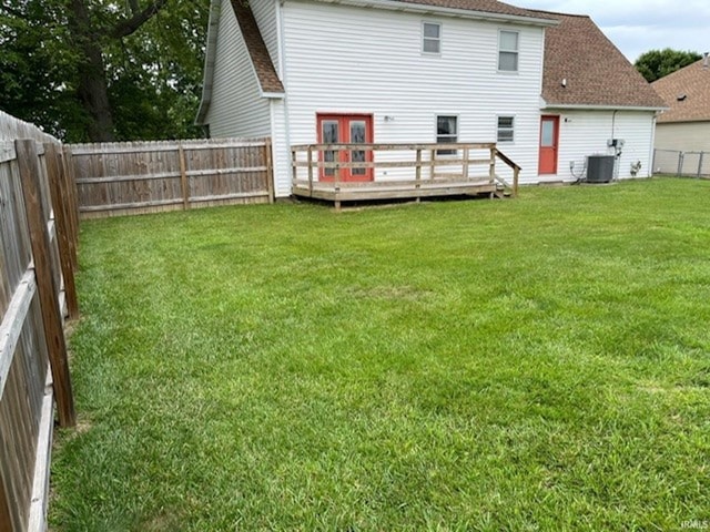 rear view of property with a wooden deck, central AC unit, and a yard