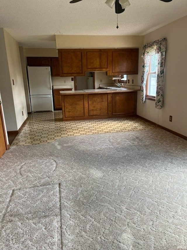 kitchen with a textured ceiling, ceiling fan, and white fridge