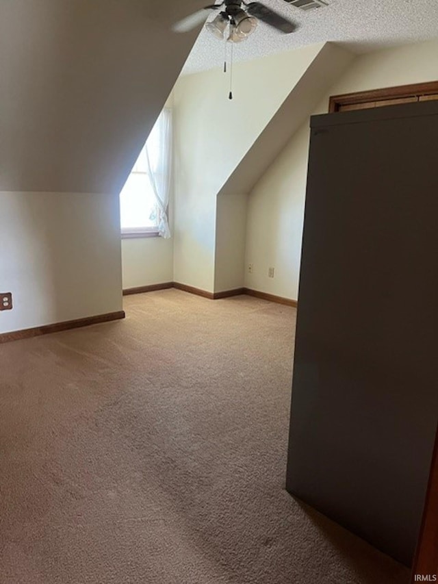 additional living space with light colored carpet, a textured ceiling, ceiling fan, and lofted ceiling