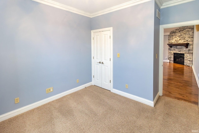 spare room with carpet, ornamental molding, and a fireplace