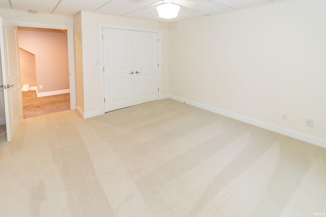 unfurnished bedroom featuring light colored carpet, a closet, and a drop ceiling