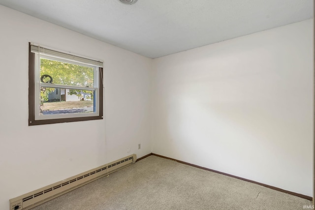 spare room with a baseboard heating unit and carpet