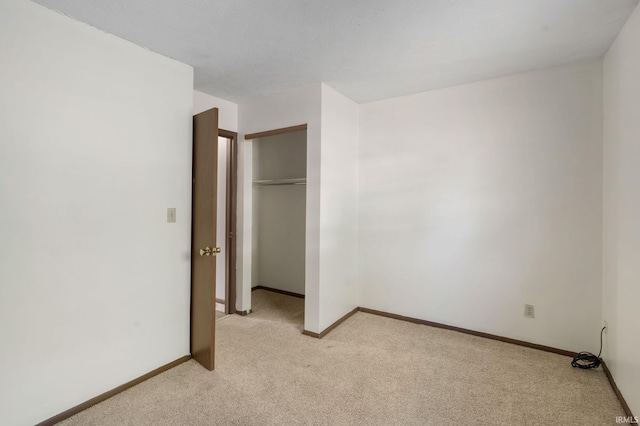 unfurnished bedroom featuring a closet and light colored carpet