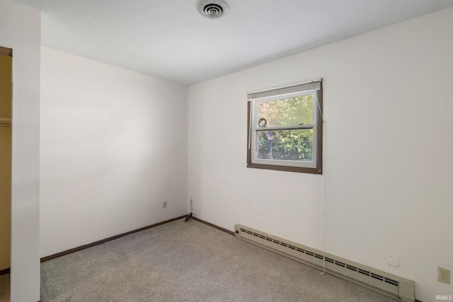 spare room with carpet flooring, a baseboard radiator, and a textured ceiling