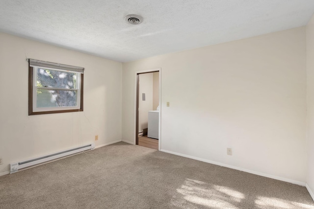 carpeted empty room with a baseboard heating unit, washer / clothes dryer, and a textured ceiling