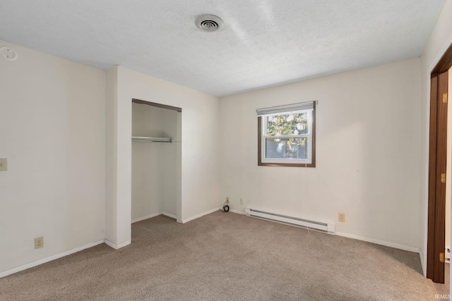 unfurnished bedroom with a textured ceiling, carpet flooring, baseboard heating, and a closet