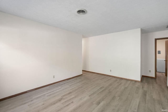 empty room with light wood-type flooring and a textured ceiling