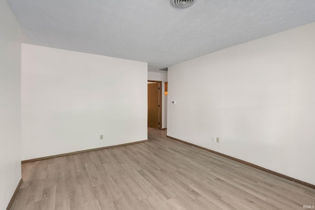 empty room with a textured ceiling and light hardwood / wood-style floors