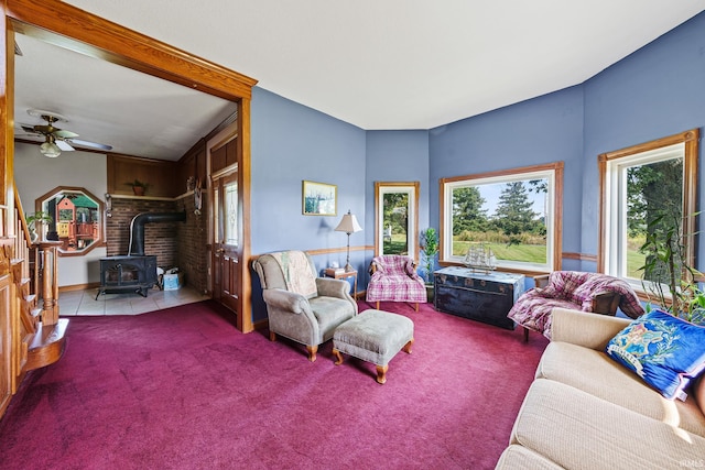 carpeted living room with ceiling fan and a wood stove