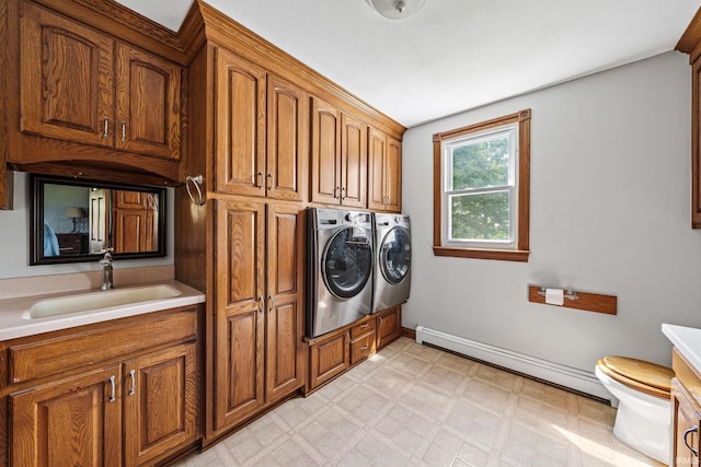 clothes washing area featuring a baseboard heating unit, washer and clothes dryer, and sink