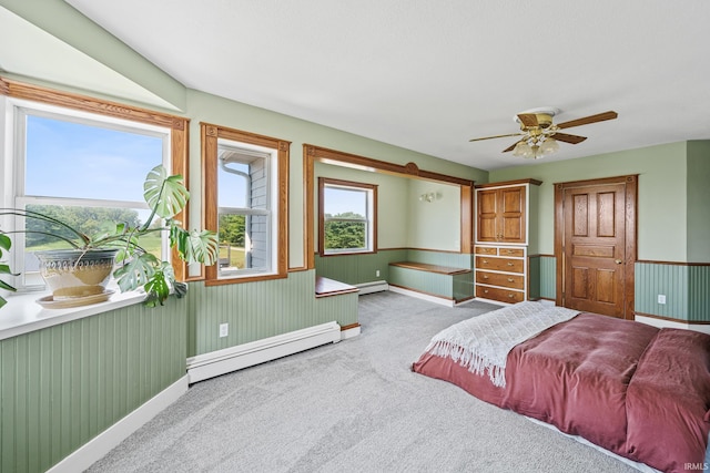 carpeted bedroom featuring a baseboard heating unit and ceiling fan