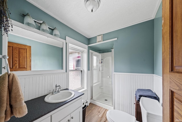 bathroom with a textured ceiling, vanity, walk in shower, toilet, and hardwood / wood-style flooring