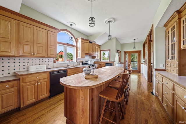 kitchen featuring dark hardwood / wood-style flooring, black dishwasher, pendant lighting, a kitchen island, and a breakfast bar