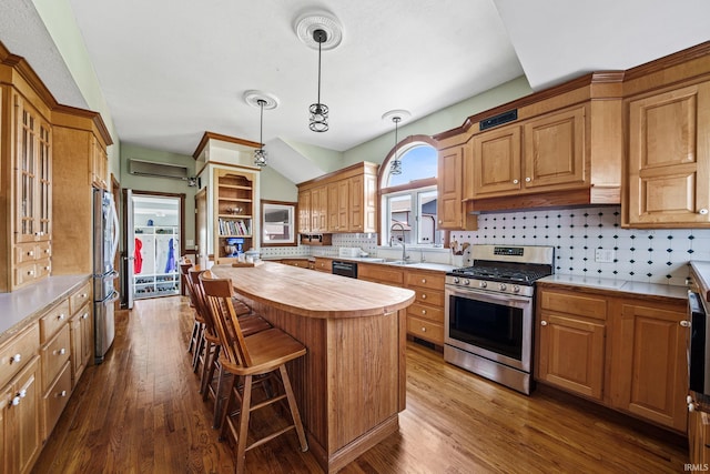 kitchen with tasteful backsplash, decorative light fixtures, a kitchen island, dark wood-type flooring, and appliances with stainless steel finishes