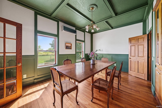 dining area with a wall unit AC, hardwood / wood-style flooring, a chandelier, coffered ceiling, and a baseboard radiator