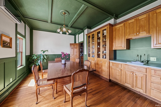 kitchen with dark hardwood / wood-style floors, hanging light fixtures, ornamental molding, sink, and a chandelier