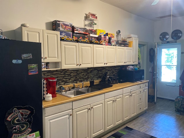 kitchen featuring black appliances, hardwood / wood-style floors, sink, decorative backsplash, and white cabinetry