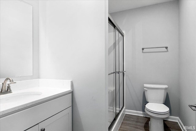 bathroom with a shower with door, vanity, toilet, and hardwood / wood-style flooring