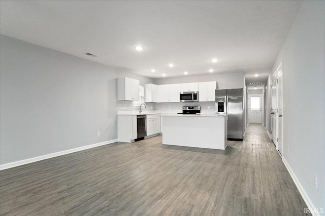 kitchen featuring a kitchen island, appliances with stainless steel finishes, hardwood / wood-style flooring, and white cabinets