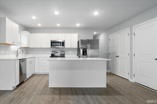 kitchen with a center island, stainless steel appliances, light wood-type flooring, and white cabinets