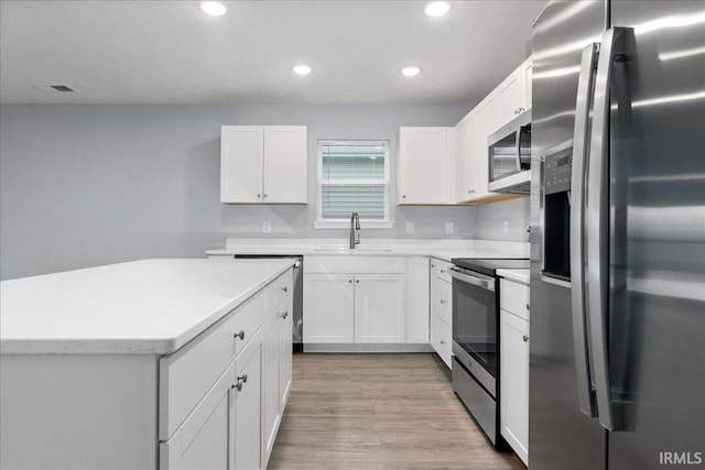 kitchen featuring stainless steel appliances, sink, light wood-type flooring, and white cabinets