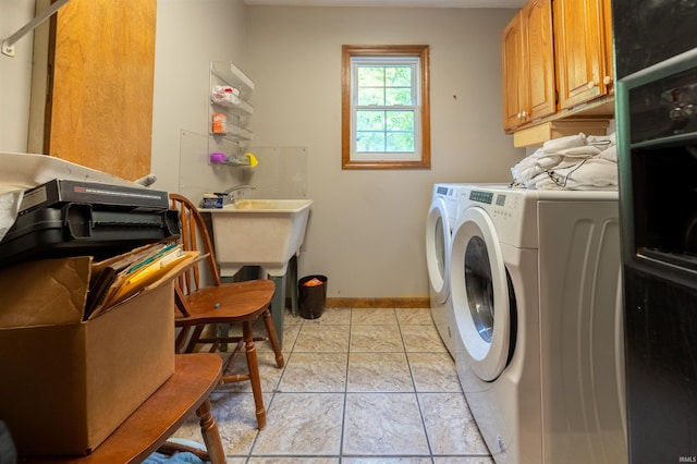 clothes washing area featuring cabinets, washer and clothes dryer, and light tile patterned floors