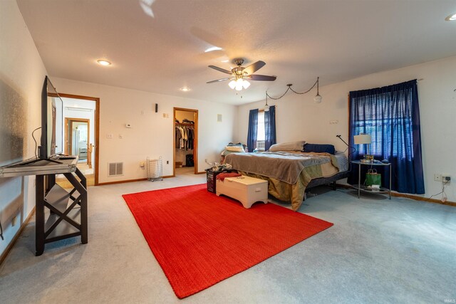 carpeted bedroom with a walk in closet, ceiling fan, and a closet