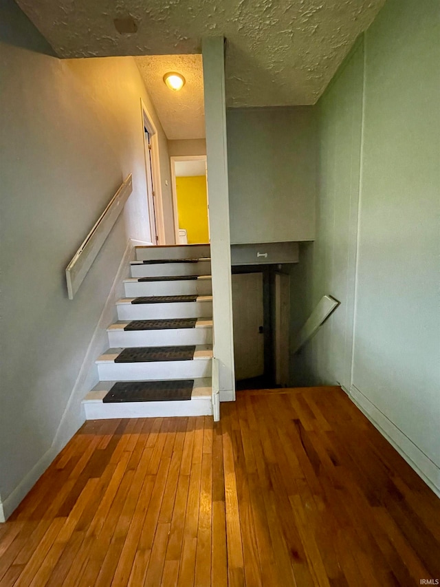 staircase with hardwood / wood-style floors and a textured ceiling