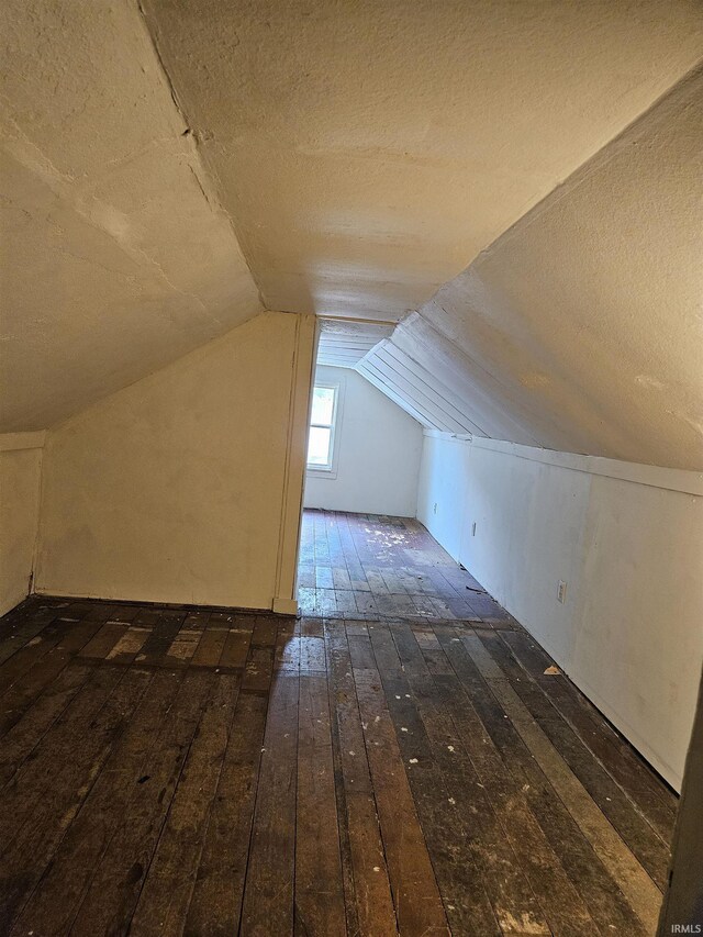 bonus room featuring lofted ceiling, dark hardwood / wood-style flooring, and a textured ceiling