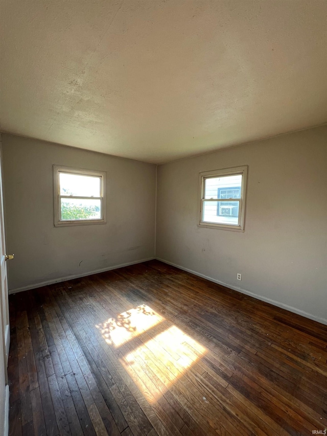 unfurnished room with a textured ceiling and dark hardwood / wood-style floors