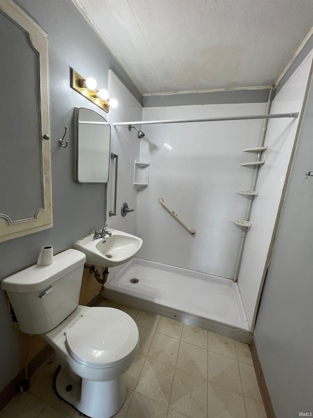 bathroom featuring toilet, a shower, sink, and a textured ceiling