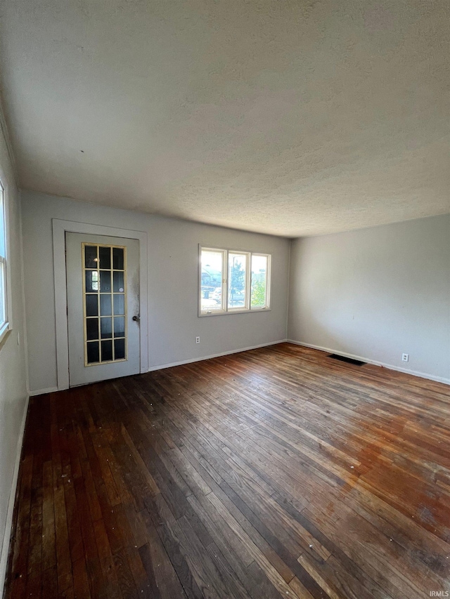 unfurnished living room with a textured ceiling and dark wood-type flooring