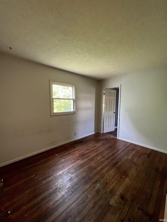 spare room with a textured ceiling and dark wood-type flooring