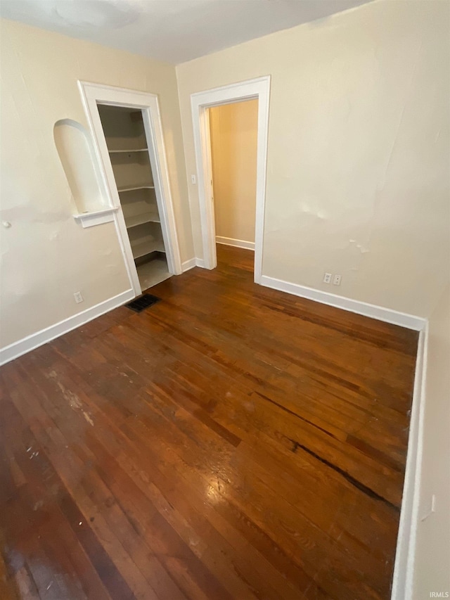 unfurnished bedroom with a closet and dark hardwood / wood-style flooring