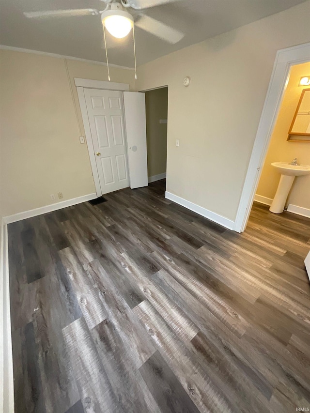 unfurnished bedroom featuring ensuite bath, dark wood-type flooring, sink, and ceiling fan