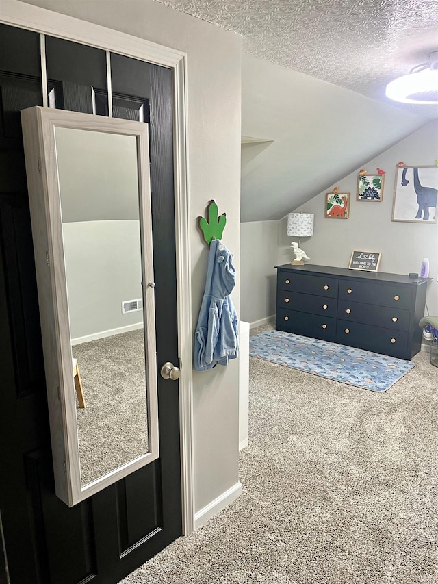 bedroom with vaulted ceiling, carpet floors, and a textured ceiling