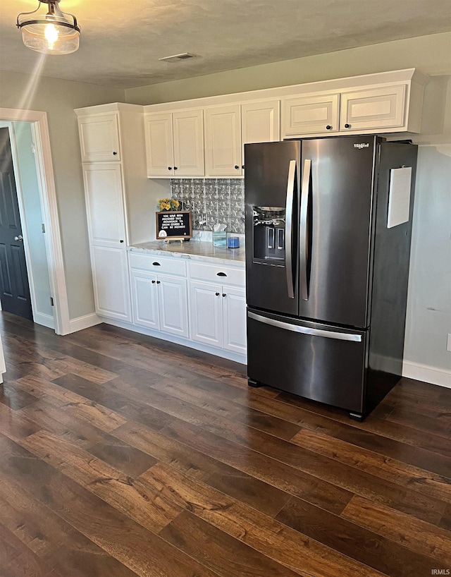 kitchen with dark wood-type flooring, white cabinets, light stone counters, and stainless steel fridge with ice dispenser