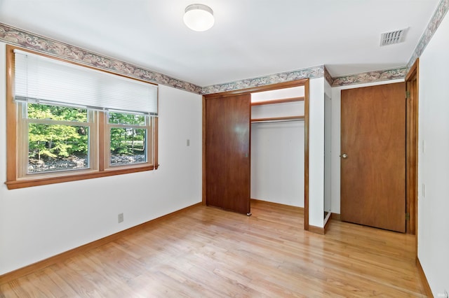 unfurnished bedroom with light wood-type flooring and a closet